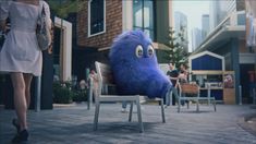 a blue stuffed animal sitting on top of a wooden chair in front of a building