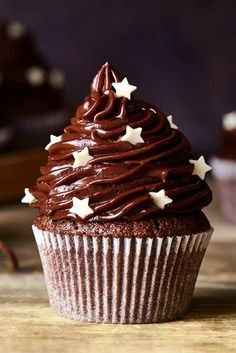 a cupcake with chocolate frosting and stars on top sitting on a wooden table