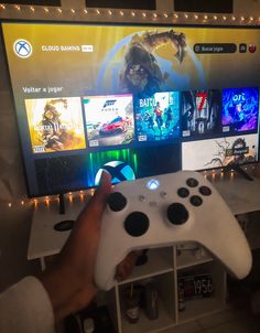 a person holding a video game controller in front of a flat screen tv with games on it