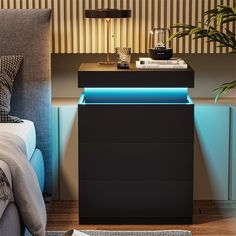 a night stand with a blue light on it next to a bed and a plant