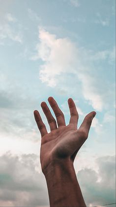 a person's hand reaching up into the sky