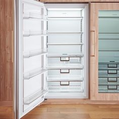 an empty refrigerator with its door open in a room that has wooden floors and walls