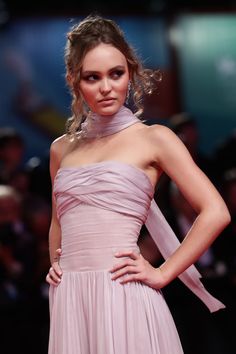 a woman in a pink dress standing on a red carpet with her hands on her hips