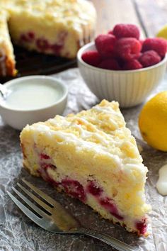 a piece of cake sitting on top of a table next to a bowl of raspberries