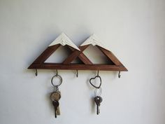 two wooden triangle shaped key holders with keys hanging from hooks on the wall next to each other