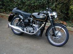 a black and gold motorcycle parked in front of some bushes