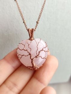 This Tree of Life pendant is handmade with a heart-shaped natural rose quartz stone. The metal part is bare copper. • Pendant size : H 2.8 x W 1.3 cm 🎁 This pendant comes with a free 20" copper chain necklace. Ready to wear or give as a gift. ✨ One-of-a-kind item ✨ There is only one of these. You will get the exact pendant as seen in the photos. CARE INSTRUCTION • Wire-wrapped jewellery is delicate, please handle it with care and avoid wearing it during activities that may bend the piece. • Aft Wire Wrap Heart Stone, Wire Wrapped Heart Stone, Journal Starters, Wire Jewelry Ideas, Heart Crystal Necklace, Polished Rocks, Wire Bending, Wire Jewerly, Heart Shaped Rocks