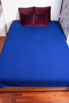 a bed with two pillows on top of it and a blue blanket over the headboard