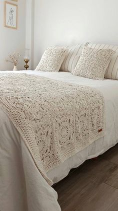 the bed is made with white linens and crocheted bedspread on it