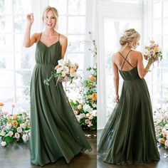 a woman in a long green dress standing next to flowers and holding a flower bouquet