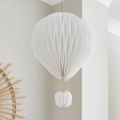 a white lamp hanging from the ceiling next to a wall with bamboo decorations on it