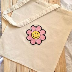 a tote bag with a smiley face drawn on the front and side, sitting on a wooden surface