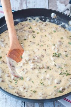 a wooden spoon in a skillet filled with cheese gravy on top of a table