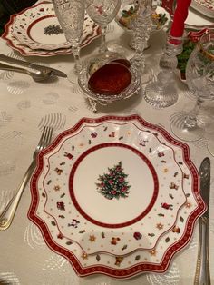 a white table topped with plates and silverware next to a christmas tree decoration on the plate