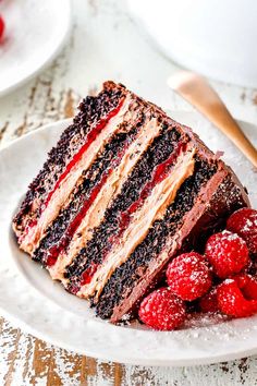 a slice of chocolate cake on a plate with raspberries