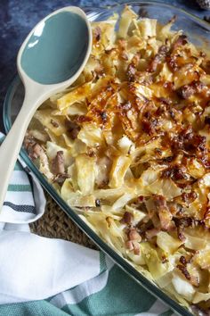 a casserole dish with meat and onions in it next to a white spoon