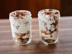 two jars filled with desserts sitting on top of a wooden table next to each other