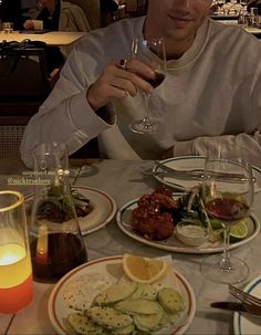 a man sitting at a table with plates of food and drinks in front of him