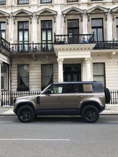 an suv parked in front of a large building with balconies on the windows