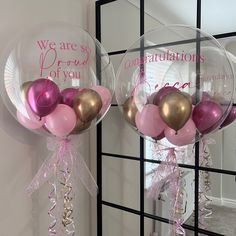 two balloons with pink, gold and silver decorations hanging from the side of a mirror