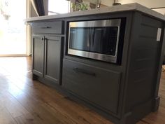 a stainless steel microwave oven sitting on top of a wooden counter next to a window