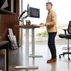 a man standing in front of a desk with a computer on it