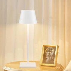 a lamp that is on top of a table next to a picture and a chair