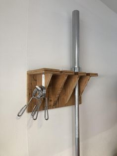 a pair of scissors are hanging on a wooden shelf with two hooks attached to it