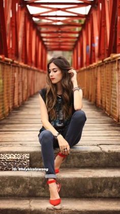 a woman sitting on some steps with her hand in her hair and wearing red shoes