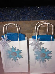 two bags with snowflakes on them sitting next to each other in front of a brick wall