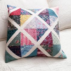 a colorful patchwork pillow sitting on top of a white couch