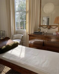 a bedroom with a bed, dresser and mirror next to a window in the room