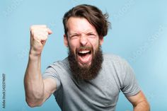 a man with a beard and grey shirt holding his fist up