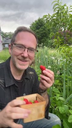 a man sitting in the grass holding a piece of fruit