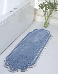 a blue bath mat sitting on top of a bathroom floor next to a white tub