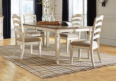 a dining room table with chairs and a rug on the floor in front of it