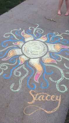 a child standing next to a sidewalk with chalk drawings on it and someone's feet in the background