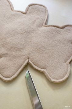 a pair of scissors sitting on top of a table next to a teddy bear shaped rug