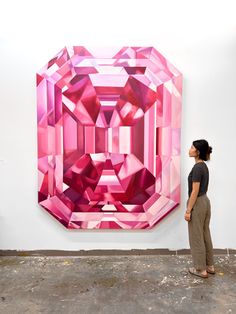 a woman standing in front of a large pink piece of art that is hanging on the wall