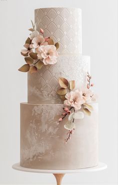 a three tiered wedding cake with pink flowers on the top and bottom, sitting on a wooden stand