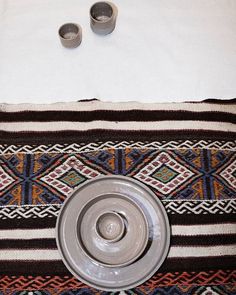 two silver cups sitting on top of a table next to a white towel and bowl