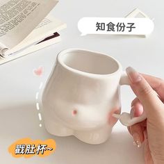 a hand holding a coffee mug with an elephant shaped handle