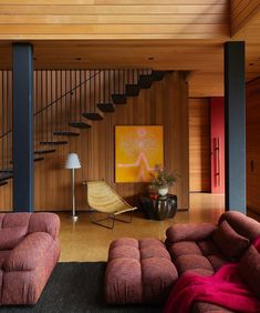 a living room filled with furniture and a stair case next to a painting on the wall