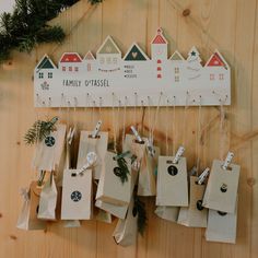 several small tags hanging on a wooden wall with christmas decorations and evergreen branches around them