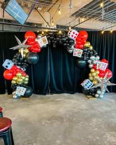 an arch made out of black, silver and red balloons with dices on them