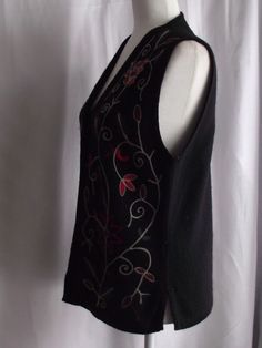 "This beautiful embroidered vest can go from casual to semi-formal with just a few quick changes. Made of a jet black wool, heavy thread, similar to cording forms the designs of flowers and foliage for wearable art. Small side seam open vent gives you more space when sitting. V-neck design with a button front makes it easy to grab and go. No stains, snags or damage. Some light pilling, typical of wool. Please view all my photos. This a Dry Clean Only Garment. Please view all my actual measuremen V-neck Top With Floral Embroidery For Winter, Casual Floral Embroidered Vest For Fall, Embroidered Sleeveless Vest For Fall, Sleeveless Embroidered Vest For Fall, Casual Fitted Vest With Floral Embroidery, Fitted Floral Embroidered Vest For Fall, Black Floral Embroidery Sleeveless Vest, Elegant Embroidered Sleeveless Vest, V-neck Winter Top With Floral Embroidery