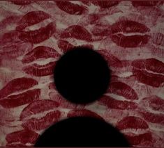 two black circles are in front of a red and white background with lipstick imprints