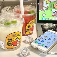 there are two cups of ice tea next to a cell phone