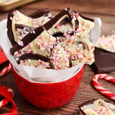 a red cup filled with white chocolate and candy canes on top of a wooden table