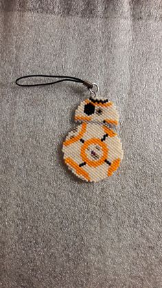 a cross stitch ornament hanging from a cord on a carpeted floor with a teddy bear in the middle